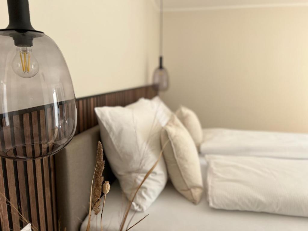 a bedroom with a bed with white pillows and a lamp at TIDE Norddeich in Norddeich