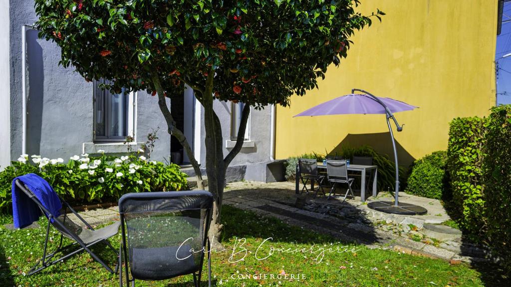 - un jardin avec une table et un parasol violet dans l'établissement MAISON LE BONHEUR Concarneau 4 personnes, à Concarneau