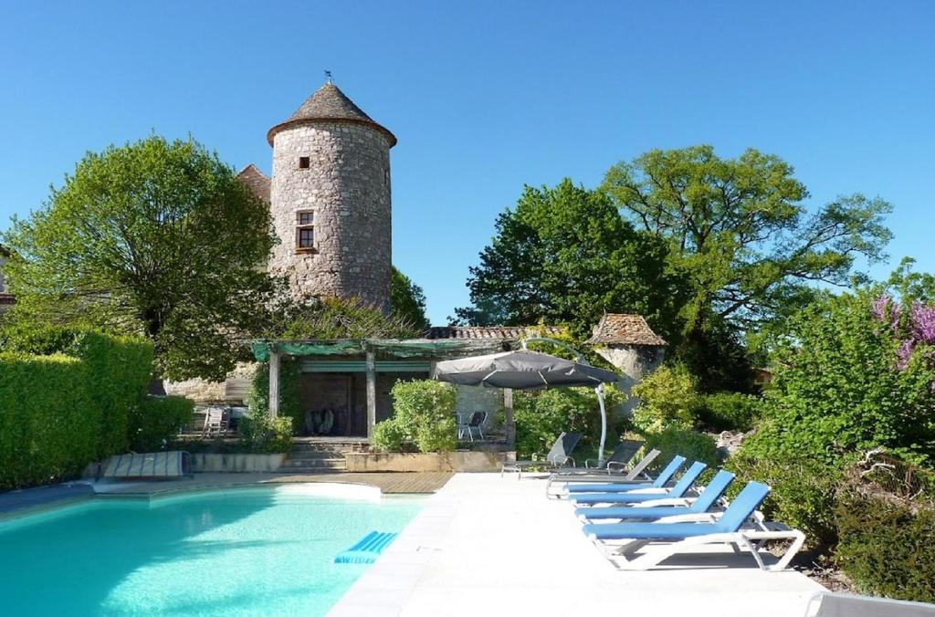 una piscina con tumbonas y un edificio con una torre en Chateau de Sadillac, en Sadillac