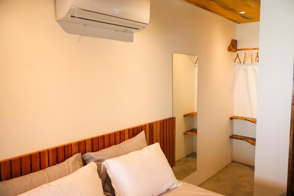 a room with a bed with white pillows and a fan at Euodoo in São Miguel dos Milagres