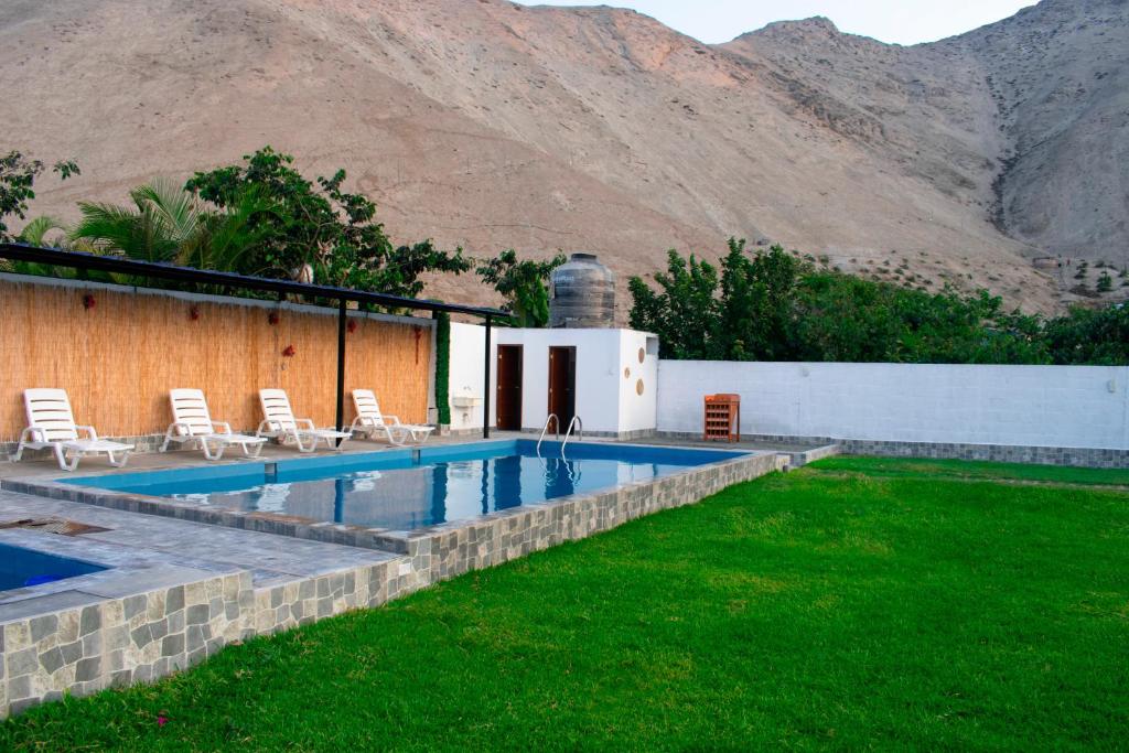 a villa with a swimming pool and mountains in the background at Kampu Wasi - Casa de Campo in Pachacamac