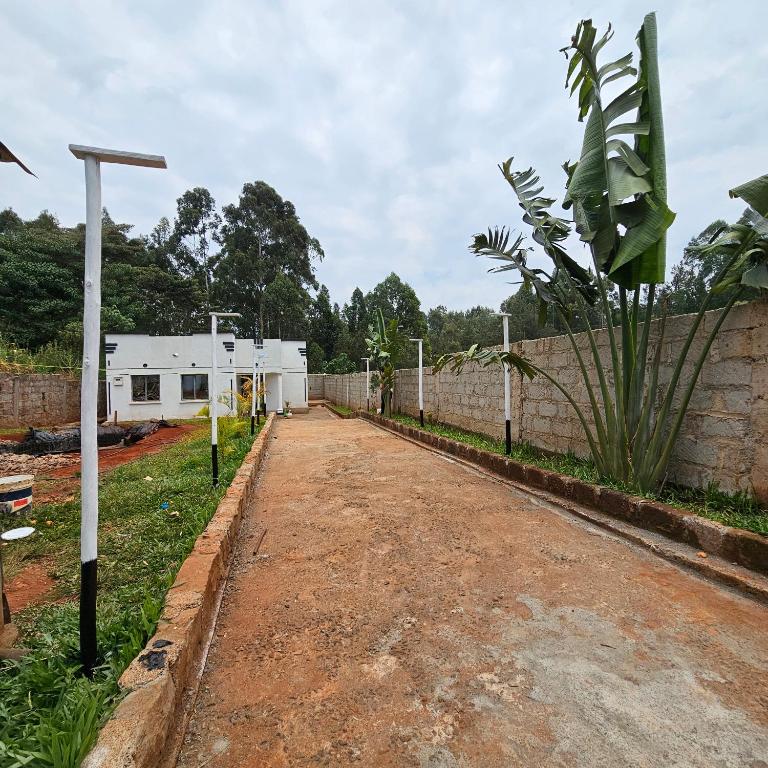 a dirt road with a fence and a building at Superhome in Nyeri