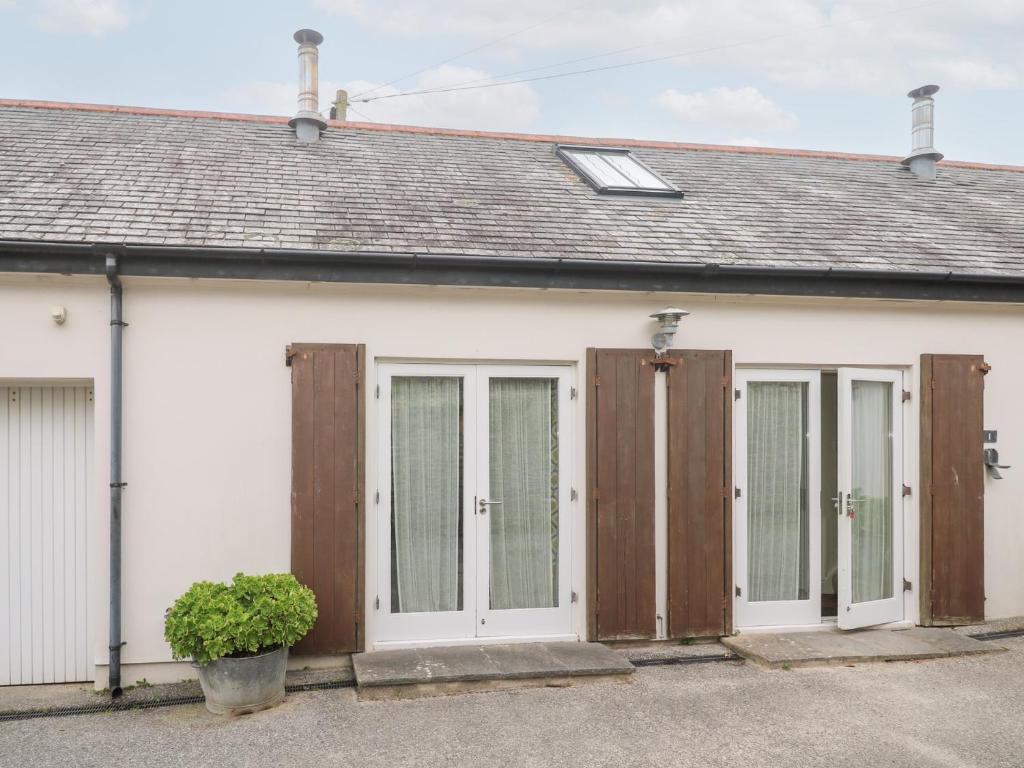 ein weißes Haus mit Holztüren und einem Dach in der Unterkunft No 1 The Hinges in Newquay