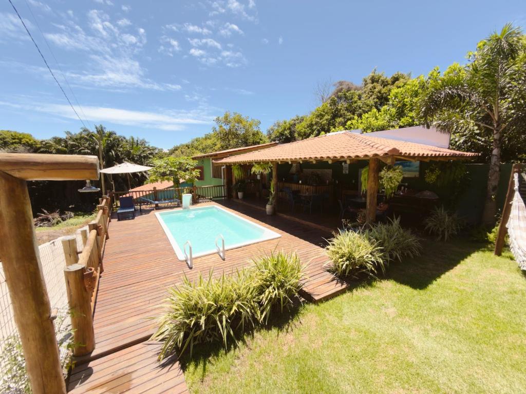 a wooden deck with a swimming pool and a house at Encanto do Mar Pousada in Caraíva