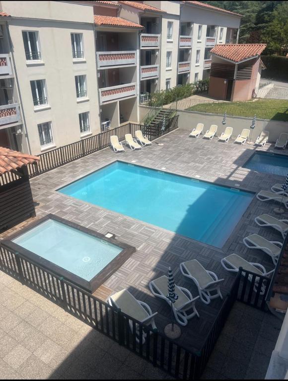 une grande piscine avec des chaises et un bâtiment dans l'établissement Le Panorama, à Gréoux-les-Bains