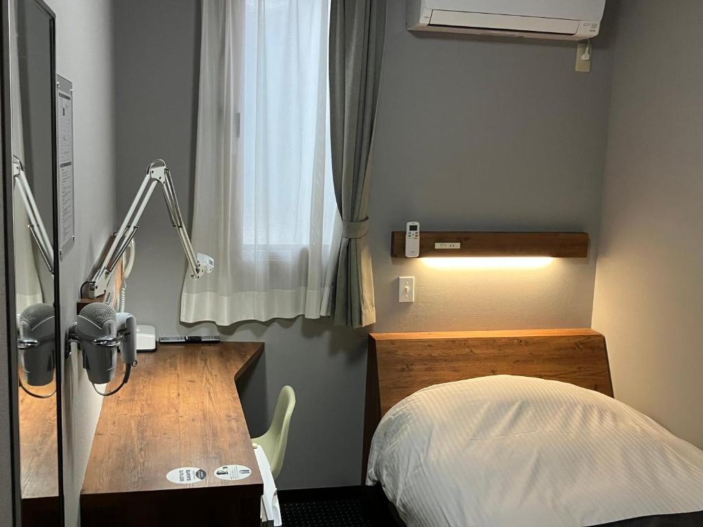 Un dormitorio con una cama, un escritorio y una lámpara. en Atto Business Hotel Ichinoseki, en Ichinoseki