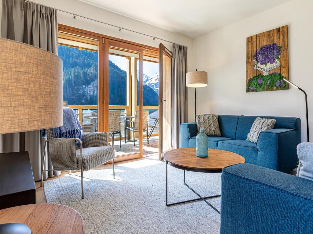 ein Wohnzimmer mit einem blauen Sofa und einem Tisch in der Unterkunft Apartment in French Alps with Wellness Centre in Abondance
