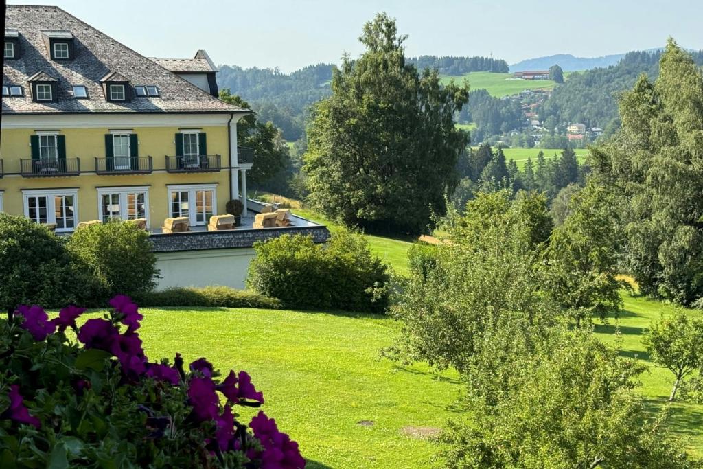 a house on a hill with flowers in the foreground at Arabella Jagdhof Resort am Fuschlsee, a Tribute Portfolio Hotel in Hof bei Salzburg