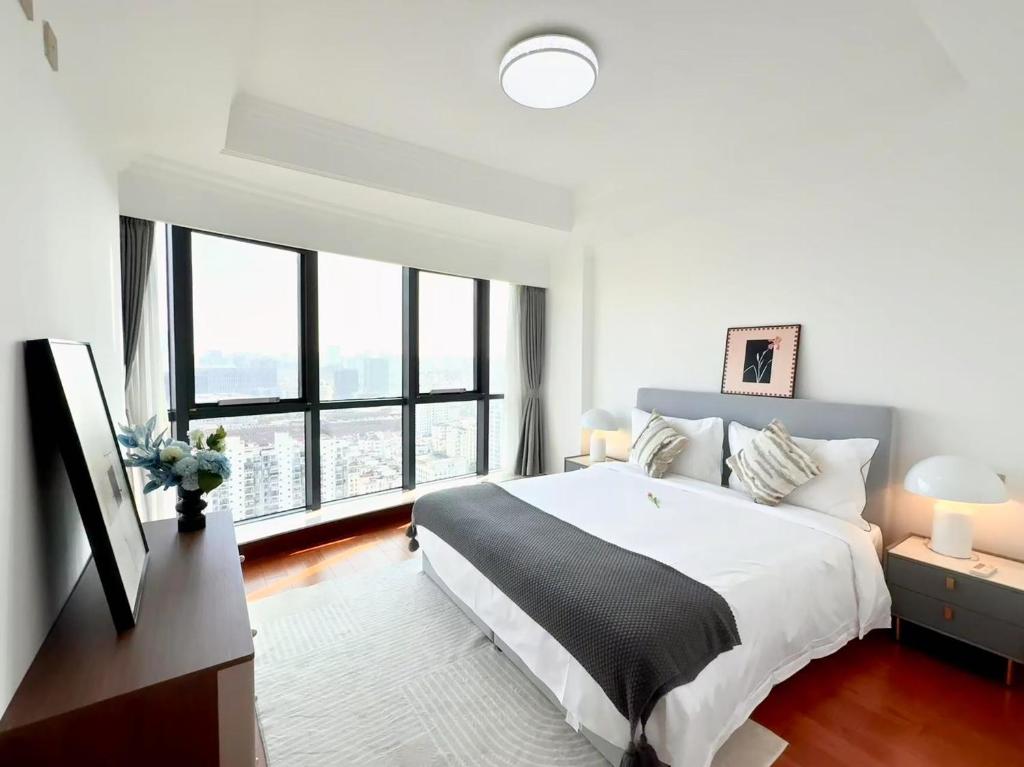 una camera da letto con un letto grande e una grande finestra di Shanghai downtown Tyms B&B Near Hongqiao Metro and Jiaotong University High view 3bedroom&2bathroom a Shanghai