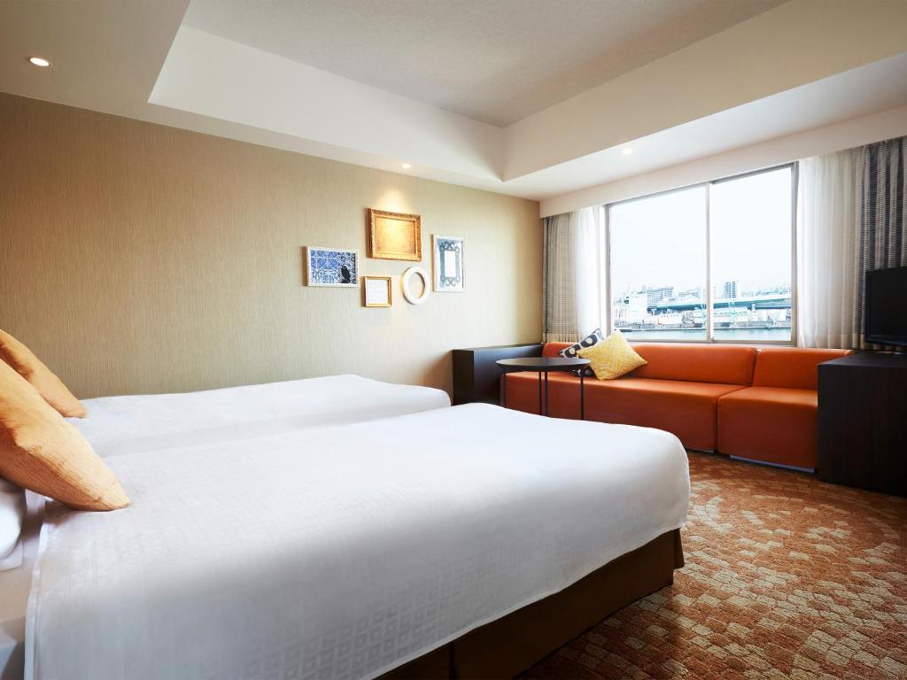 a hotel room with two beds and a couch at Hotel Universal Port in Osaka