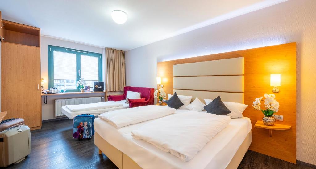 a hotel room with a large bed with white pillows at PLAZA INN Braunschweig City Süd in Braunschweig