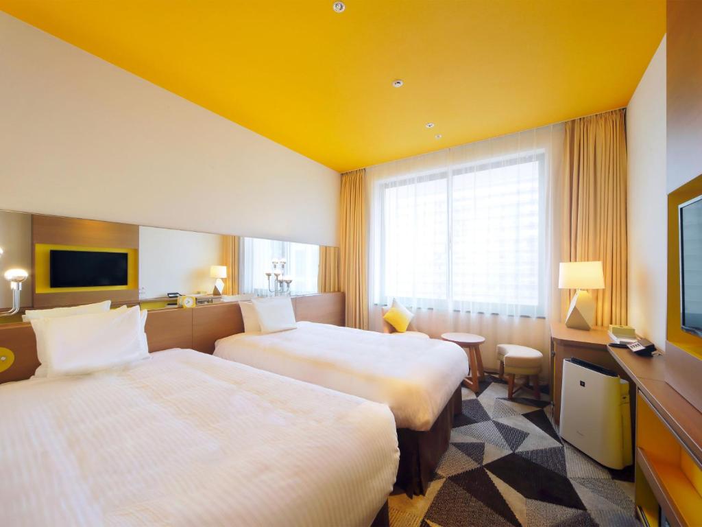 a hotel room with two beds and a television at Hotel Universal Port Vita in Osaka