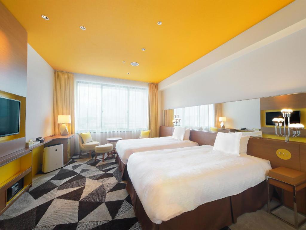 a hotel room with two beds and a television at Hotel Universal Port Vita in Osaka
