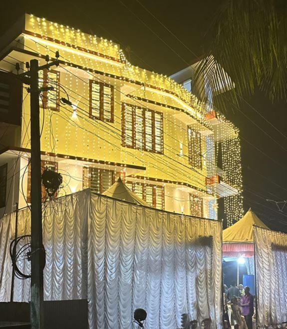 AlleppeySreeragam residency cherthala的一座黄色的大建筑,前面有白色窗帘