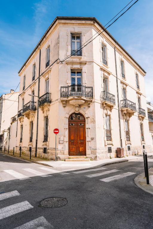 un grand bâtiment avec une porte en bois dans une rue dans l'établissement Demeure & Confort by Les Demeures de Rachel, à Nîmes