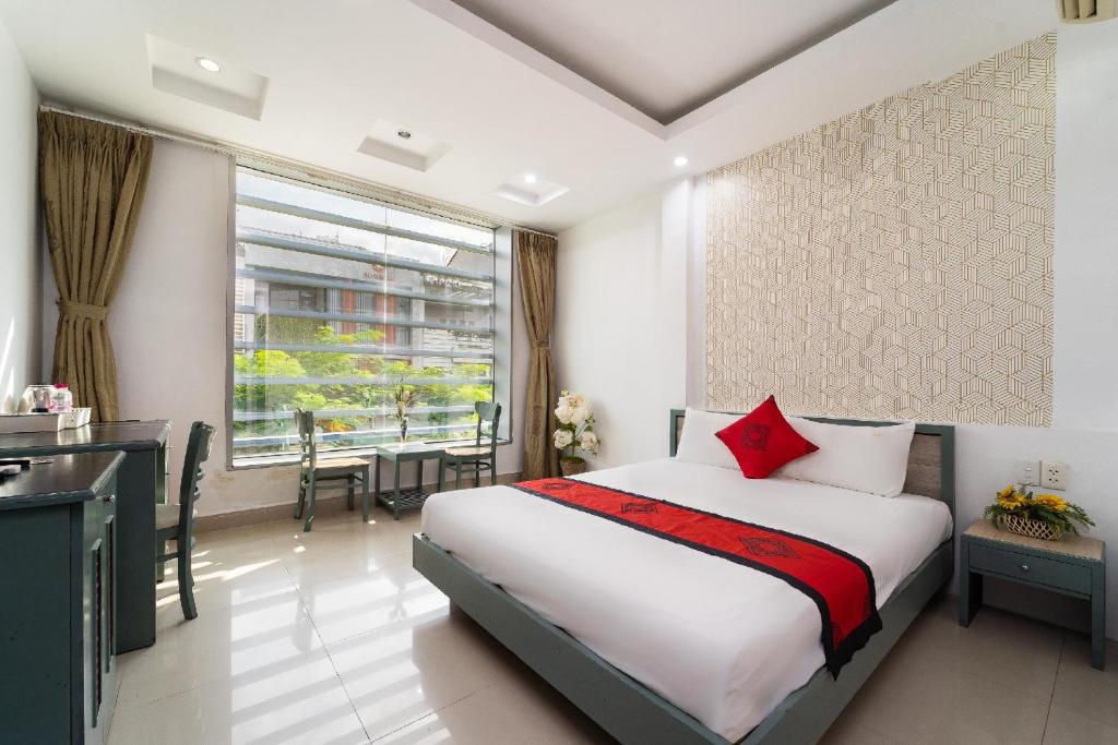 a bedroom with a bed and a desk and a window at Collection O Cozy 5 Hotel - Near SECC in Ho Chi Minh City