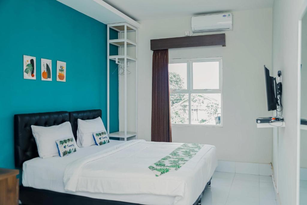 a bedroom with a large white bed with a blue wall at RedDoorz at Tienery Guest House in Tanjungkarang