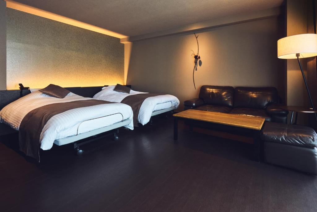 a hotel room with two beds and a couch at Oita Onsen Business Resort Kyuan - Vacation STAY 50156v in Oita