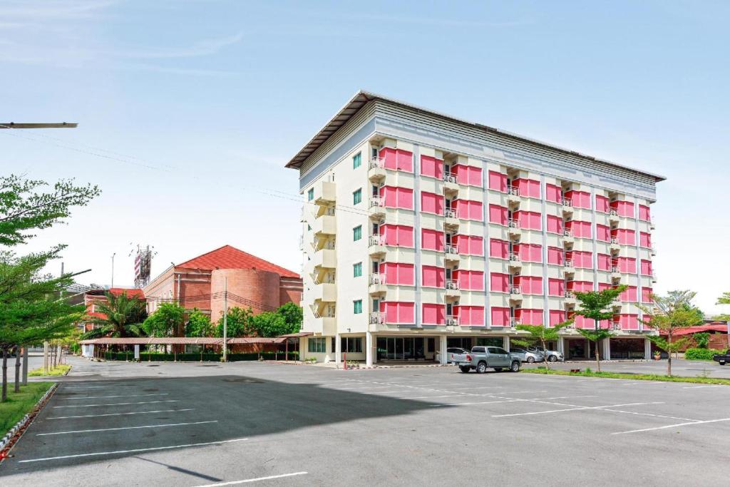 a large building with pink windows in a parking lot at Collection O VResotel in Nonthaburi