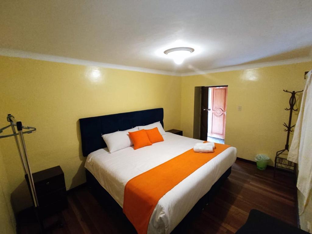 une chambre avec un grand lit avec des oreillers orange dans l'établissement Qosqo Apartments 3, à Cusco