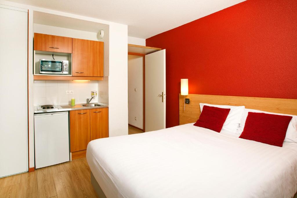 サン・ジュニ・プイイにあるセジュール ＆ アフェール ジュネーブ サン ジェニーの白いベッドと赤い壁が備わるベッドルーム1室が備わります。
