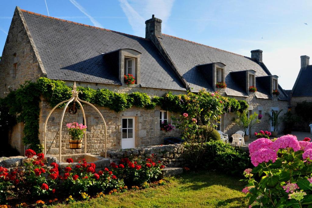 una vieja casa de piedra con flores delante en Ferme de Poulpeye, en Loctudy