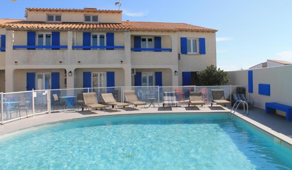 una piscina con sillas y un edificio en Hotel Le Bleu Marine en Saintes-Maries-de-la-Mer