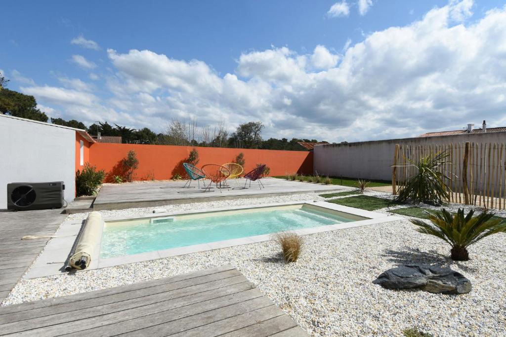 Un patio trasero con piscina y terraza de madera. en Maison pour 10 avec piscine chauffée, en La Barre-de-Monts