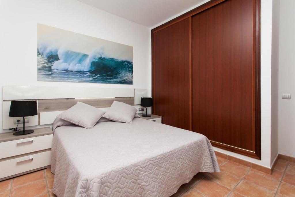 sypialnia z łóżkiem i dużą drewnianą szafką w obiekcie Villas & Apartamentos Tao Mazo w mieście Lajares