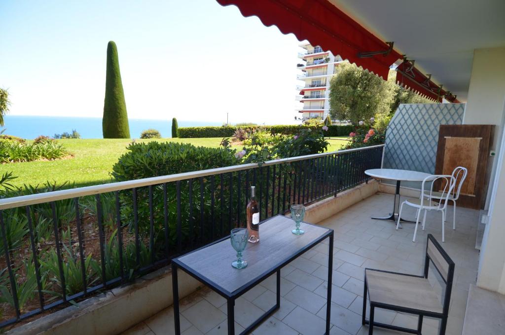 - un balcon avec une table et deux chaises ainsi qu'une bouteille de vin dans l'établissement SIRIUS - Exceptionnelle vue mer dans les hauteurs de Nice, à Nice