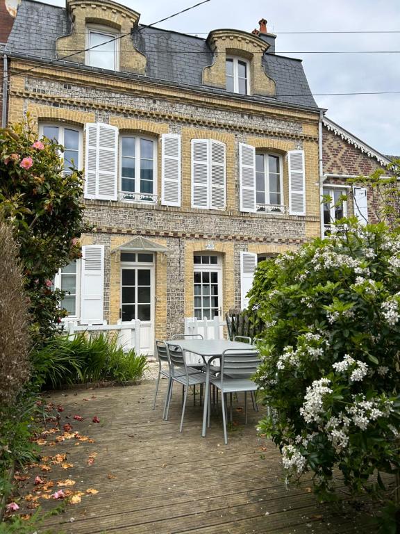a table and chairs in front of a brick building at Villa Roc Vaudieu - Charmante maison de pêcheurs in Étretat