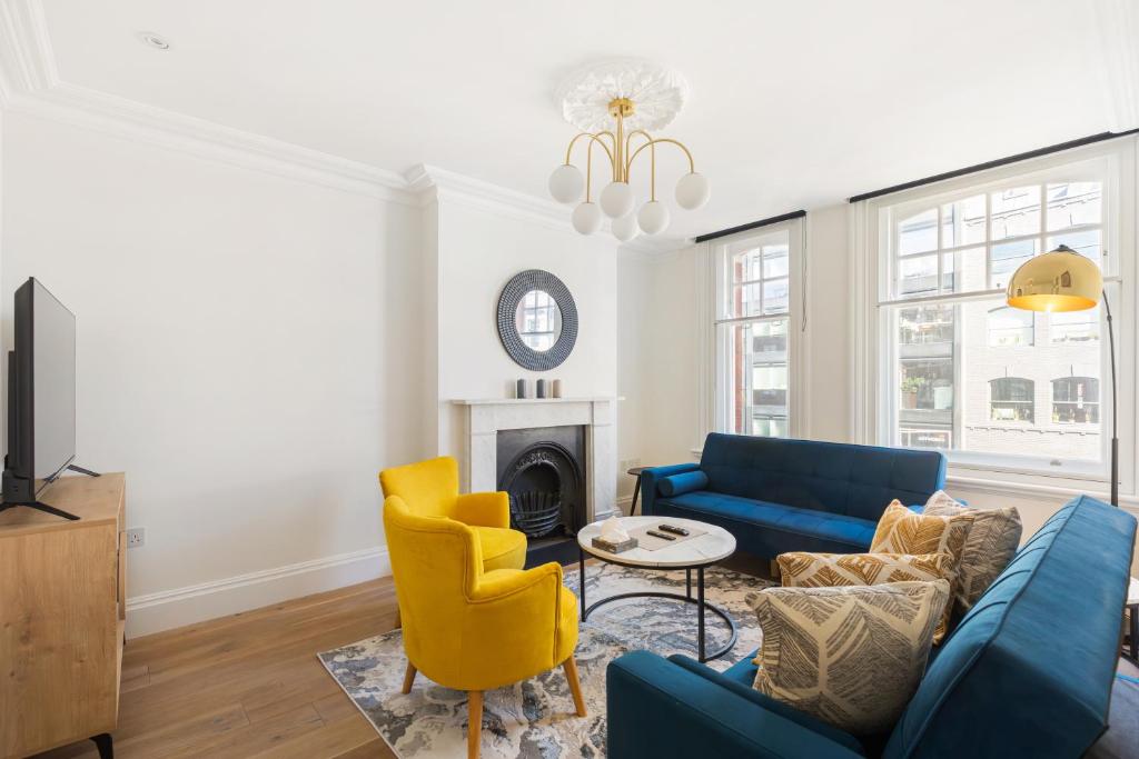 a living room with a blue couch and yellow chairs at HAFH in Farringdon- Stylish 1Bedroom Apartments in London