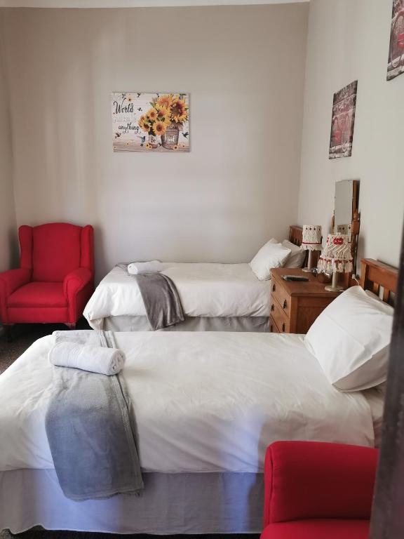 a room with two beds and a red chair at Zonneblom Guest House in Middelburg