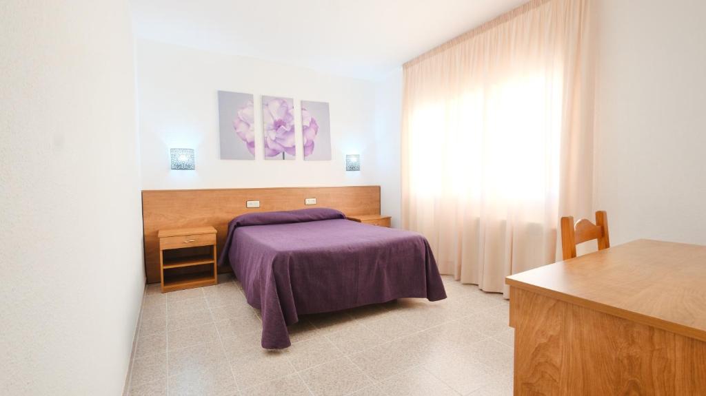 a bedroom with a bed with a purple blanket at Hotel Paradís in Torredembarra