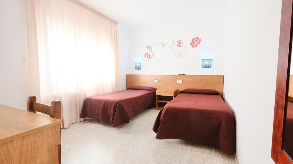 a hotel room with two beds and a window at Hotel Paradís in Torredembarra