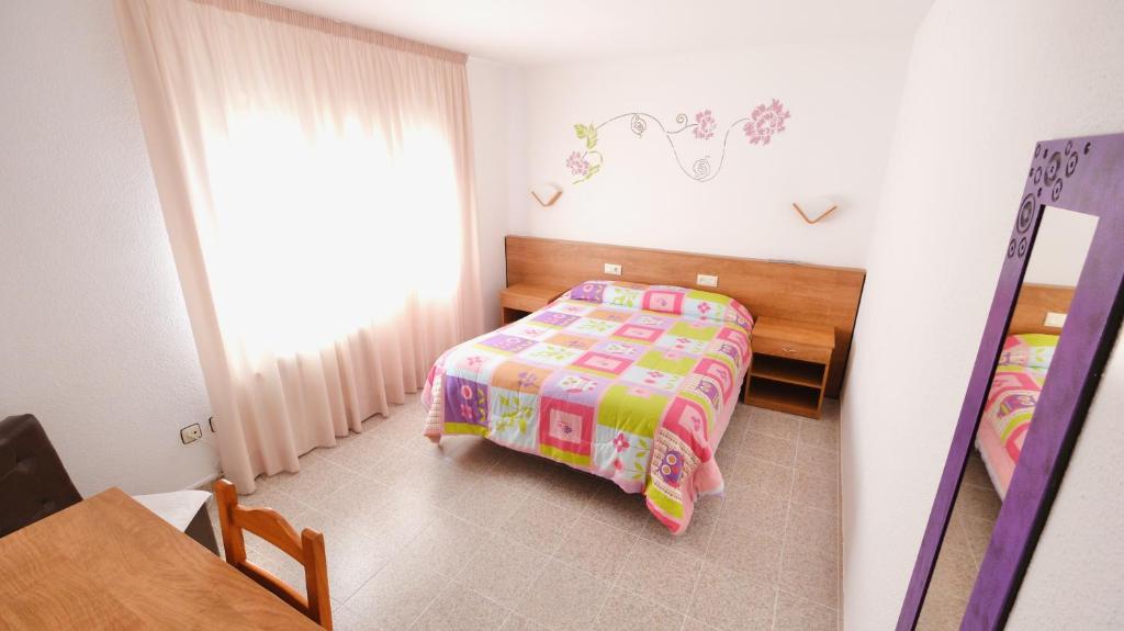 a small bedroom with a bed and a table at Hotel Paradís in Torredembarra