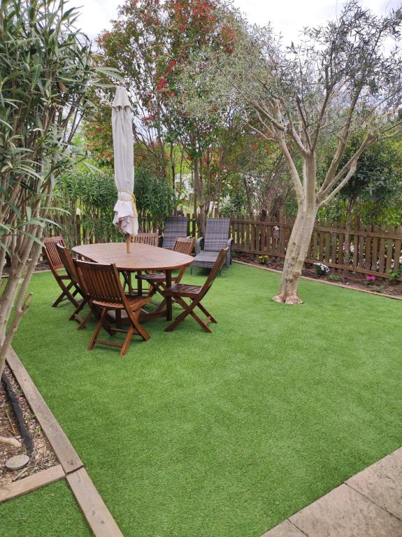 une table avec des chaises et un parasol sur une pelouse dans l'établissement Mobil-Home de Jean-Michel et Nicole, à Hyères