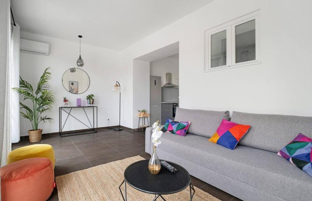 - un salon avec un canapé gris et des oreillers colorés dans l'établissement Havre de paix pour 4, clim et balcon, Caluire, à Caluire-et-Cuire