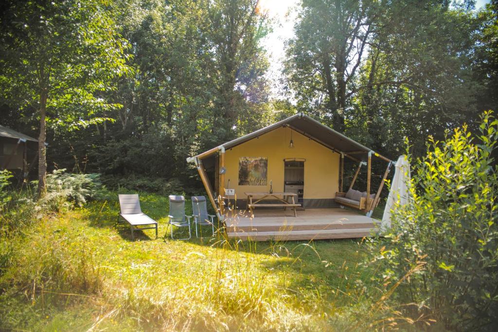 une petite maison jaune au milieu d'un champ dans l'établissement Camping Domaine le Peyral - Pionier Lodge XL, à La Salvetat-sur-Agout