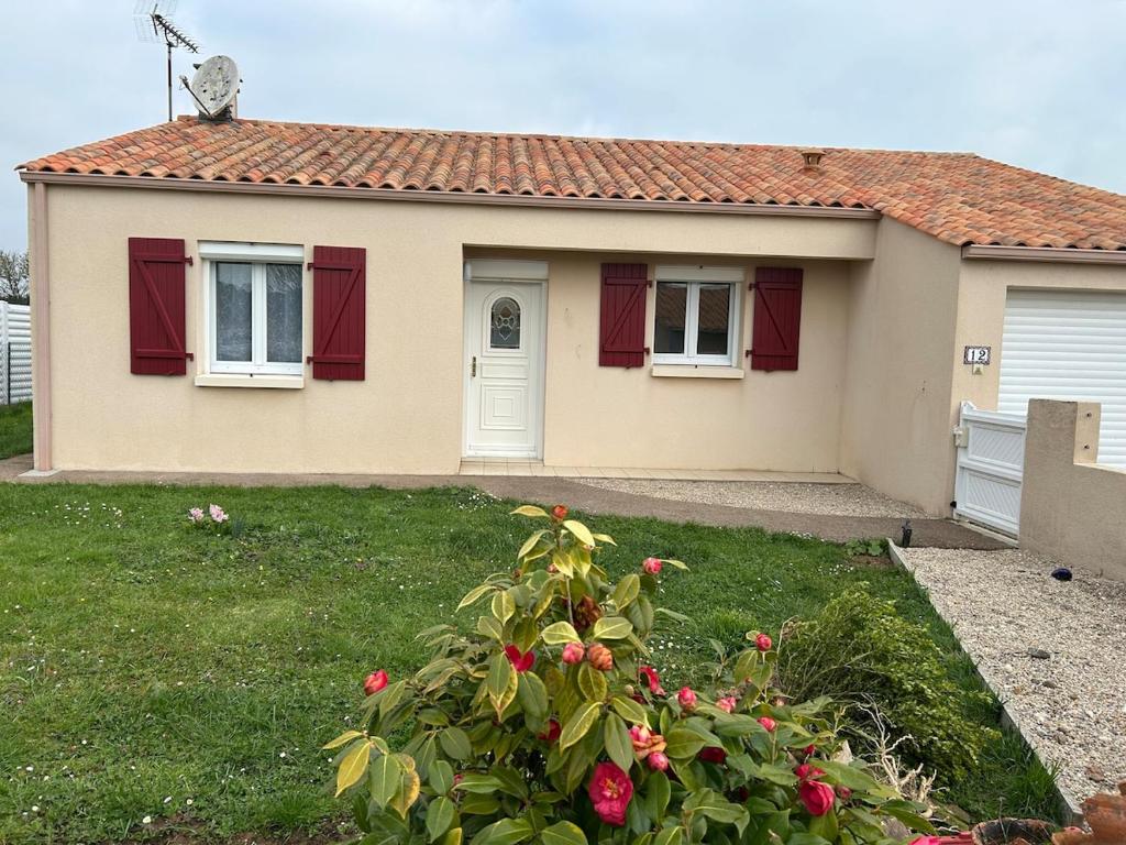 une maison avec des portes rouges et une cour verdoyante dans l'établissement Charmante maison, à Jard-sur-Mer