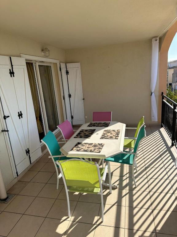 une table blanche et des chaises sur un balcon dans l'établissement CASA LOUNA 2 Pièces à 200 m de la plage et du centre vile, à Sari-Solenzara