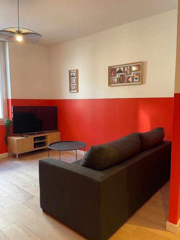 un salon avec un canapé et une télévision à écran plat dans l'établissement L'Intemporel, à Clermont-Ferrand