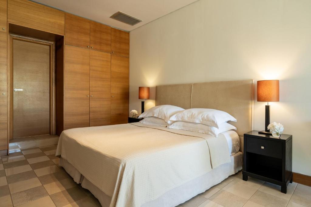 a bedroom with a large bed with white sheets and pillows at Plaza Resort in Anavyssos