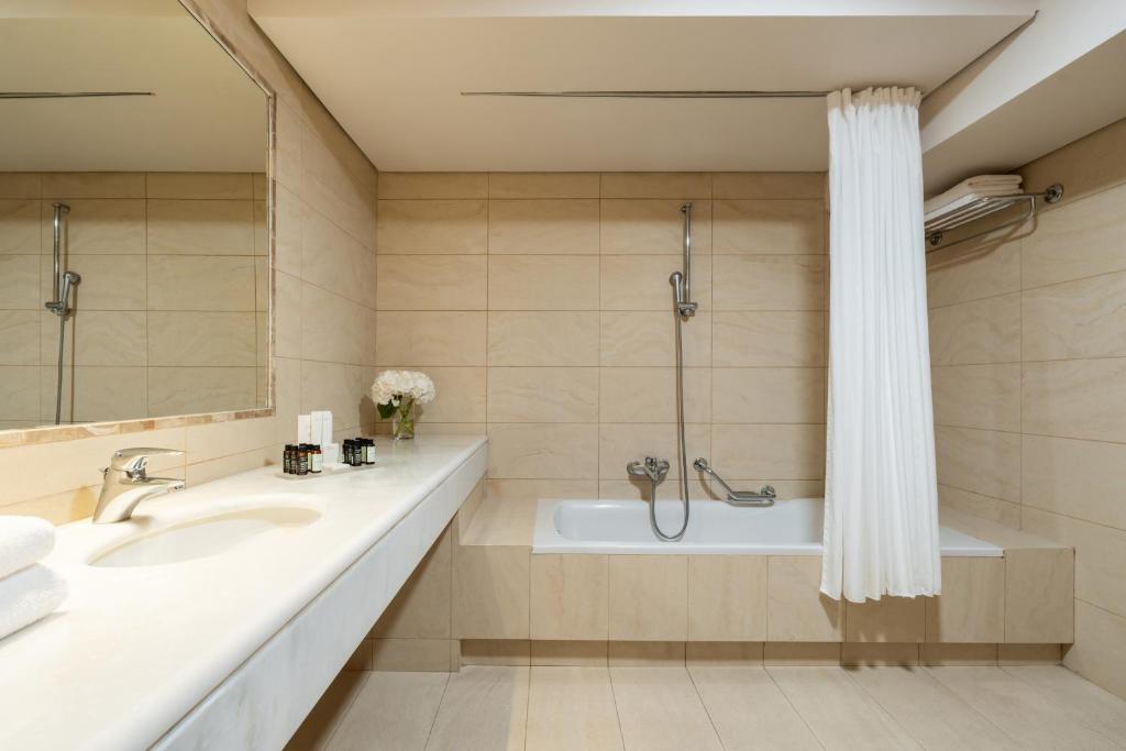 a bathroom with a tub and a sink and a shower at Plaza Resort in Anavyssos