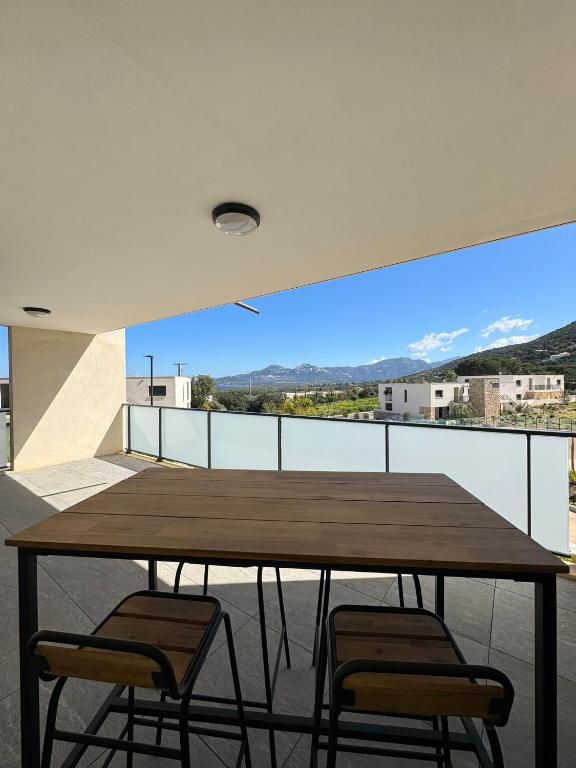 une table en bois et deux chaises sur un balcon dans l'établissement Appartement dans résidence avec piscine, à Calvi