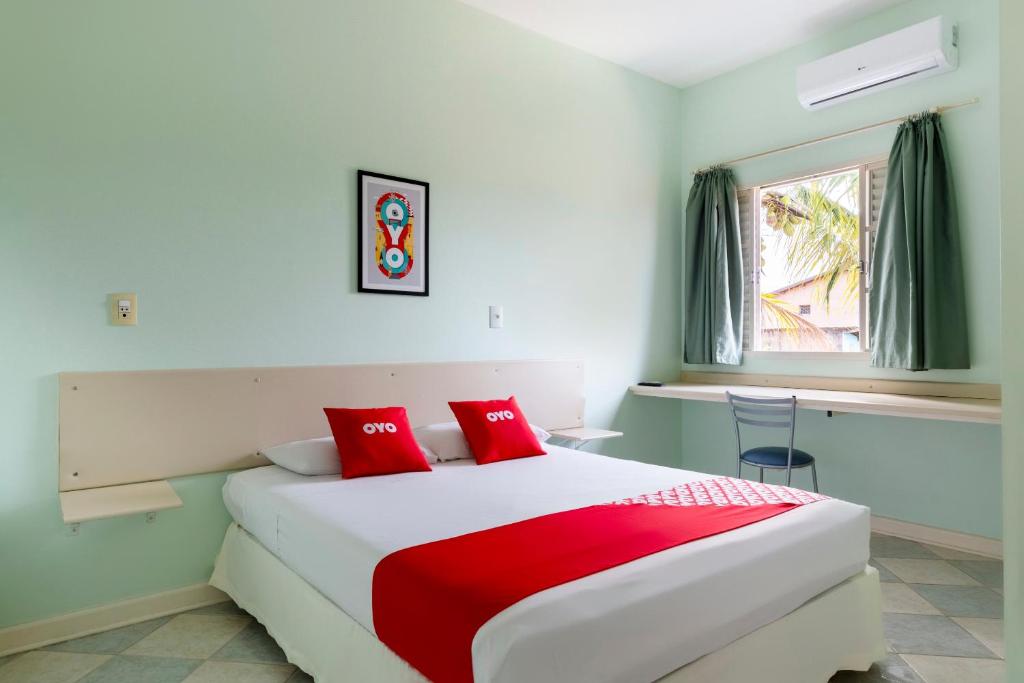 a bedroom with a large bed with red pillows at OYO Hotel Cosmópolis, Sao Paulo in Cosmópolis