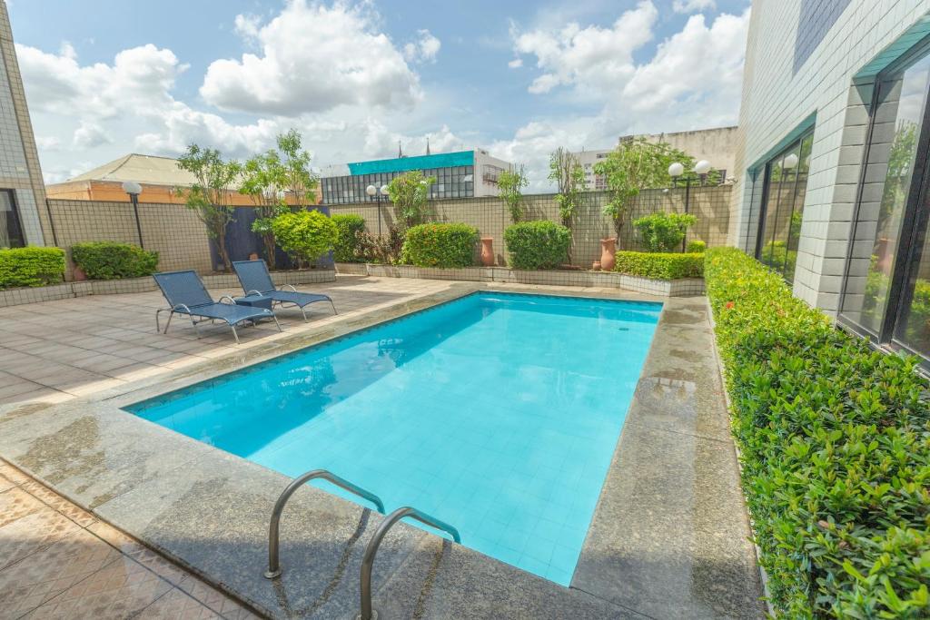 Una piscina con dos sillas al lado de un edificio. en Rede Andrade Real, en Teresina