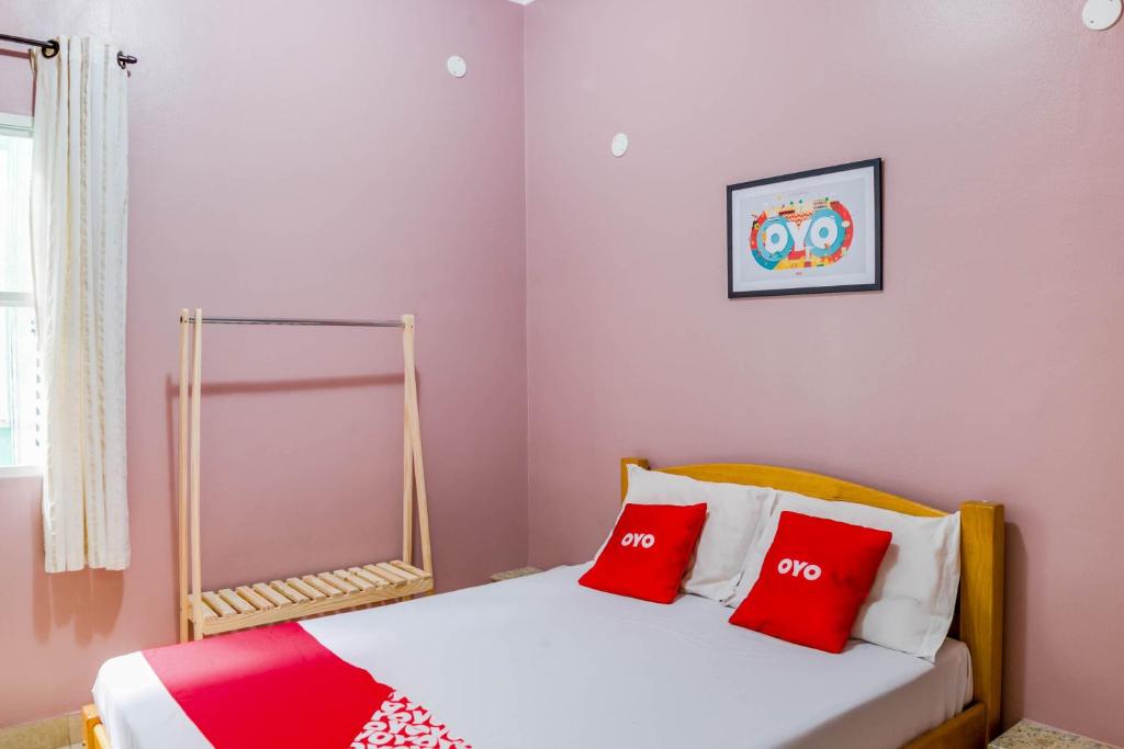 a bedroom with a bed with red and white pillows at OYO Hotel Lindoia, Petropolis in Petrópolis