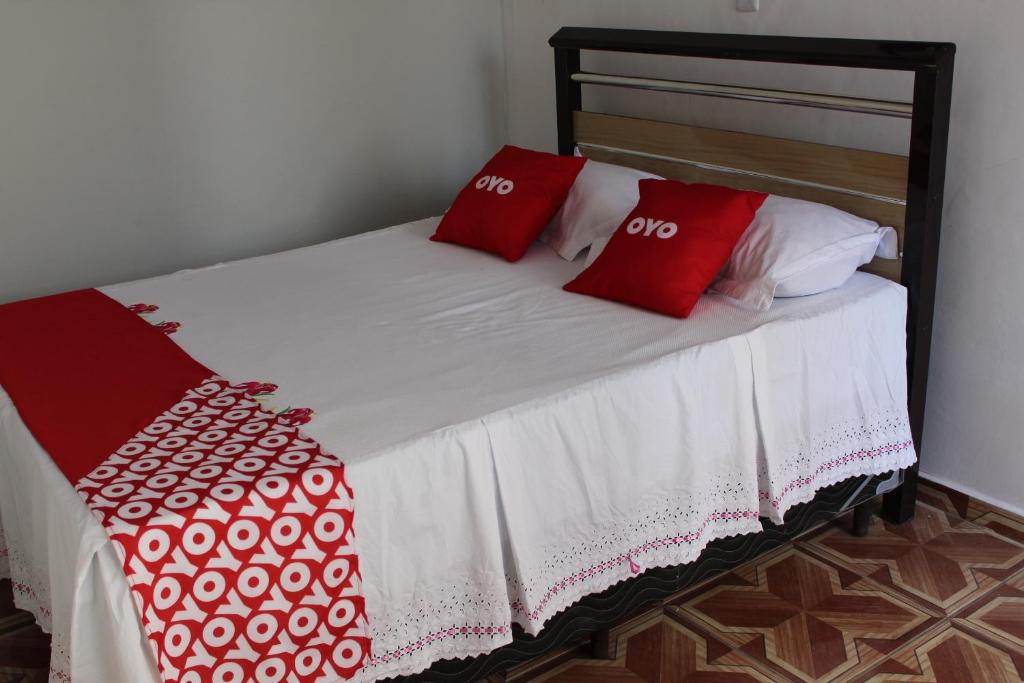 Una cama con dos almohadas rojas. en OYO Pousada Paraná, Cuiabá, en Cuiabá