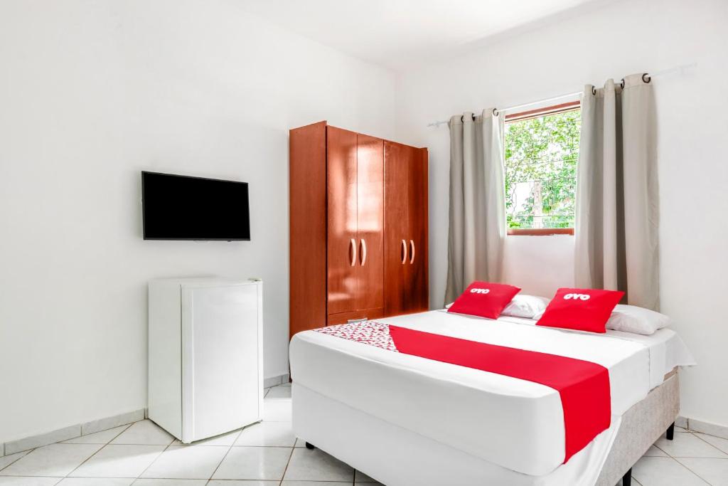 a bedroom with a large bed with red pillows at OYO Pousada Tia Léo Campinas in Campinas